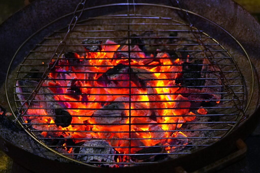 Close up of an open barbecue grill over orange-hot and black coals.